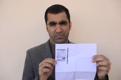 In this photo taken on October 15, 2018, Afghan public servant Ghulam Farooq Adil poses for a picture as he holds his id card or Tazkira registered to vote in the upcoming parliamentary election, in Herat province. Bloody violence has forced thousands of polling centres to close and stopped millions of people from registering to vote. But war-torn Afghanistan's long-delayed legislative election will still go ahead on October 20, officials say. Almost nine million people are eligible to vote in the ballot, which is more than three years late and largely funded by the international community.
 / AFP / HOSHANG HASHIMI
