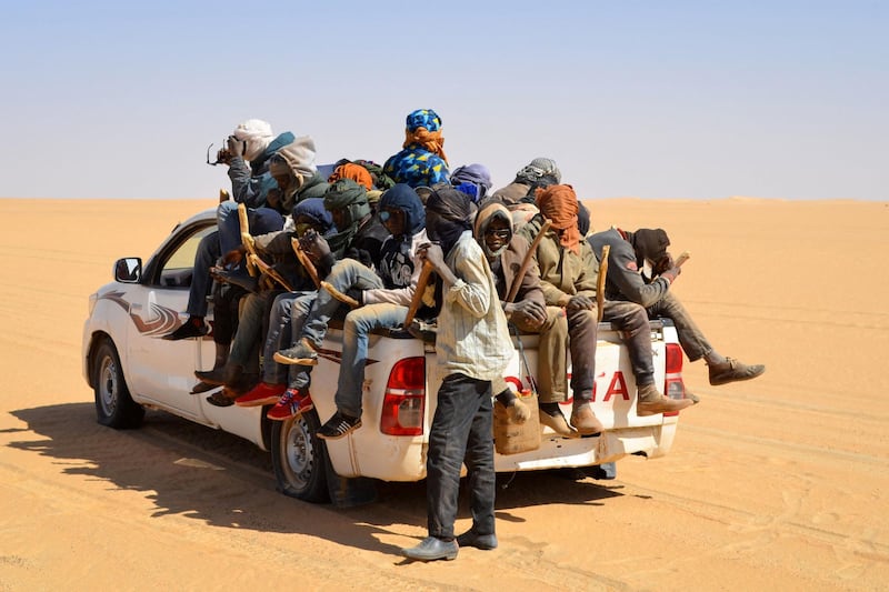 A group of migrant men, mainly from Niger and Nigeria, sit in the back of a pick up, on January 22, 2019 during a journey across the Air dessert, northern Niger, towards the Libyan border post of Gatrone. (Photo by Souleymane AG ANARA / AFP)