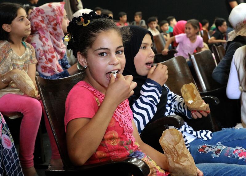 Children eat popcorn as they await the screening of a film at the Cinema Zaatari. AFP