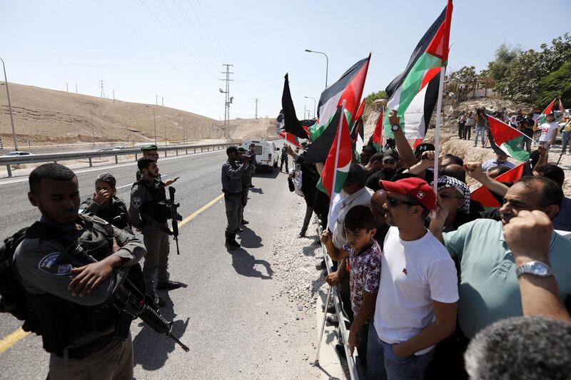 epa07037204 Demonstrators wave Palestinian flags in front of Israeli troops as they protest against Israel's plan to demolish the Palestinian Bedouin village of Khan al-Ahmar, located between the West Bank city of Jericho and Jerusalem near the Israeli settlement of Maale Adumim, 21 September 2018. Khan al-Ahmar is a Bedouin community where some 180 people live in shacks, which Israeli authorities claim were built without obtaining permits. Israeli authorities plan to demolish the shacks after the Israeli High Court of Justice rejected petitions filed by Khan al-Ahmar residents against their evacuation.  EPA/ABED AL HASHLAMOUN