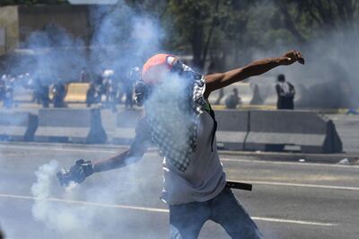 An opposition demonstrator throws a tear gas canister during clashes with soldiers loyal to Venezuelan President Nicolas Maduro after troops joined opposition leader Juan Guaido in his campaign to oust Maduro's government, in front of La Carlota military base in Caracas on April 30, 2019. Guaido -- accused by the government of attempting a coup Tuesday -- said there was "no turning back" in his attempt to oust President Nicolas Maduro from power. / AFP / Matias DELACROIX
