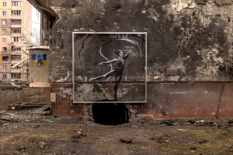 Graffiti created by British artist Banksy under a protective screen on the damaged wall of a residential building in Irpin, Ukraine in April 2023. Getty Images