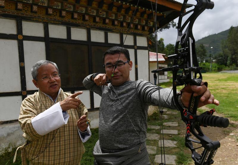 In this photo taken on August 25, 2018, president of the Bhutan Indigenous Games and Sports Association (BIGSA), Kinzang Dorji (L), explains how a compound bow works during an interview with AFP at the Changlimithang Archery Ground in Thimphu. The traditional sport is a way of life for some 800,000 people in the small Himalayan kingdom of Bhutan. - TO GO WITH Bhutan-archery-lifestyle,FEATURE by Abhaya Srivastava
 / AFP / ARUN SANKAR / TO GO WITH Bhutan-archery-lifestyle,FEATURE by Abhaya Srivastava
