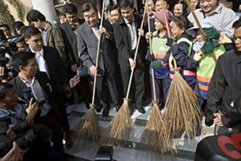 Thailand's Prime Minister Abhisit Vejjajiva, centre, along with caretaker prime minister Chawarat Chandeerakul, centre left, participate in a staged clean-up of Government House on Dec 19, 2008, in Bangkok, Thailand.