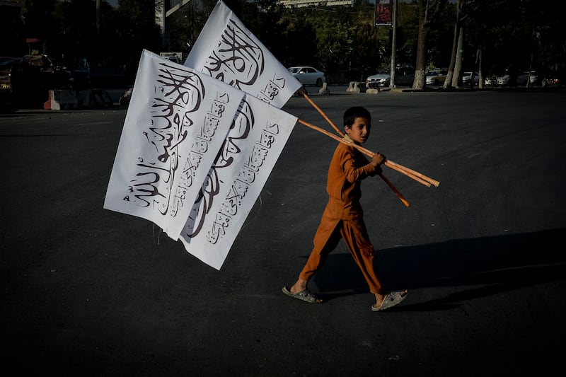 A boy carries Taliban flags to sell at the Karte Mamorin area of Kabul. AFP