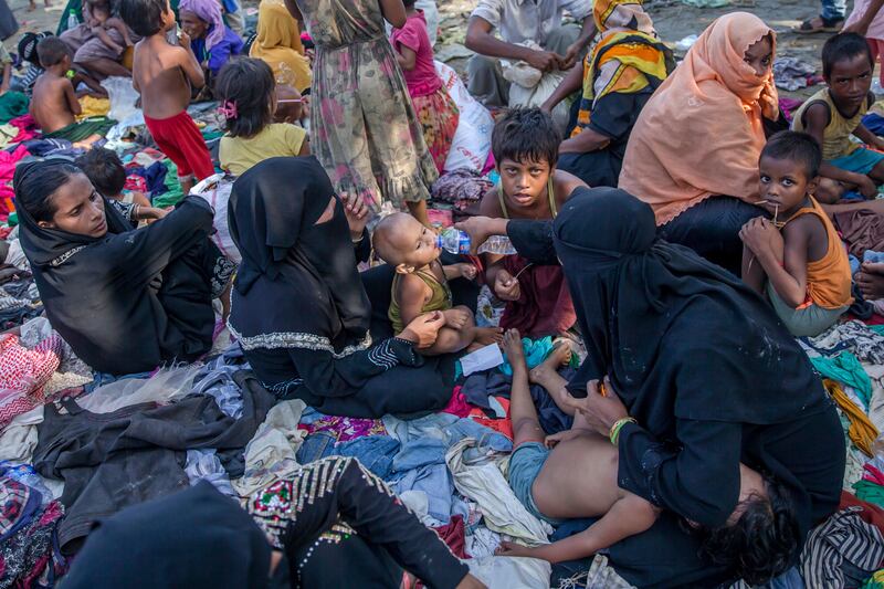 Newly arrived Rohingya Muslims, who crossed over from Myanmar into Bangladesh, rest on clothes that were earlier distributed to other refugees at Teknaf, Bangladesh, Saturday, Sept. 16, 2017. The U.N. has described the violence against the Rohingya in Myanmar as ethnic cleansing, a term that describes an organized effort to rid an area of an ethnic group by displacement, deportation or killing. (AP Photo/Dar Yasin)