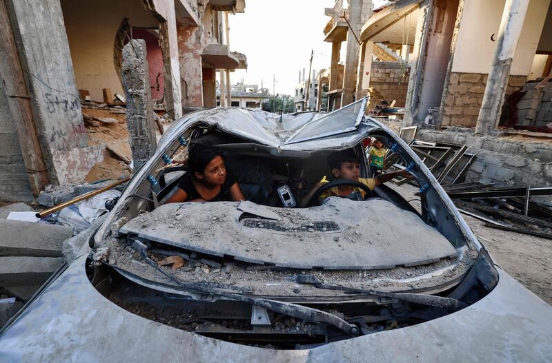 Palestinian children play inside a car destroyed during the May 2021 conflict between Hamas and Israel. AFP