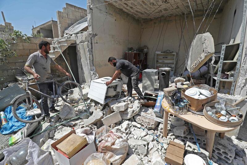 Abu Abdullah (C), a Syrian displaced from the town of Khan Sheikhun in the south of the northwestern Idlib province, inspects his belongings at his now-destroyed home upon returning during a temporary truce, in Khan Sheikhun on August 3, 2019. Damascus resumed air strikes on northwest Syria's Idlib on August 5, a war monitor said, scrapping a ceasefire for the jihadist-run bastion and accusing its opponents of targeting an airbase of its ally Russia. / AFP / Omar HAJ KADOUR
