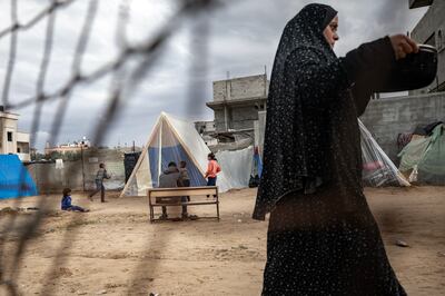 A woman walks by as Palestinian children play next to their tents in the Rafah camp in the southern Gaza Strip. EPA