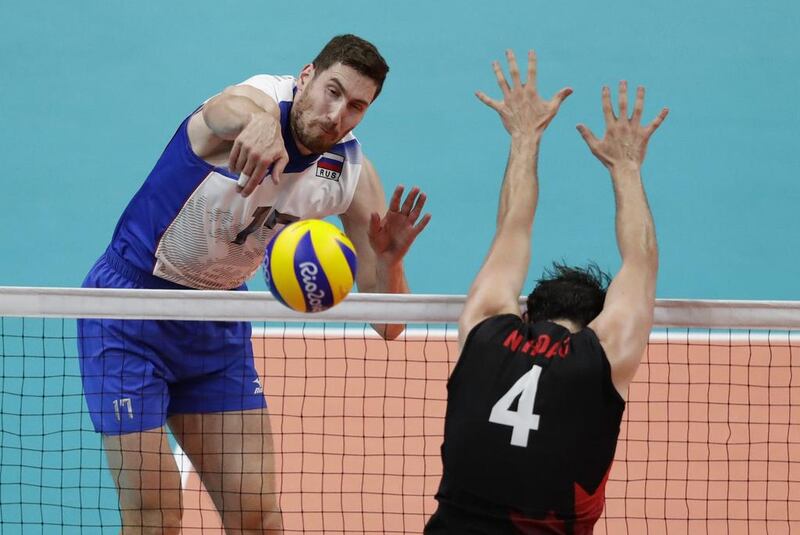 Russia’s Maxim Mikhaylov spikes the ball at Canada’s Nicholas Hoag in the men’s quarter-final volleyball match. Robert F Bukaty / AP Photo