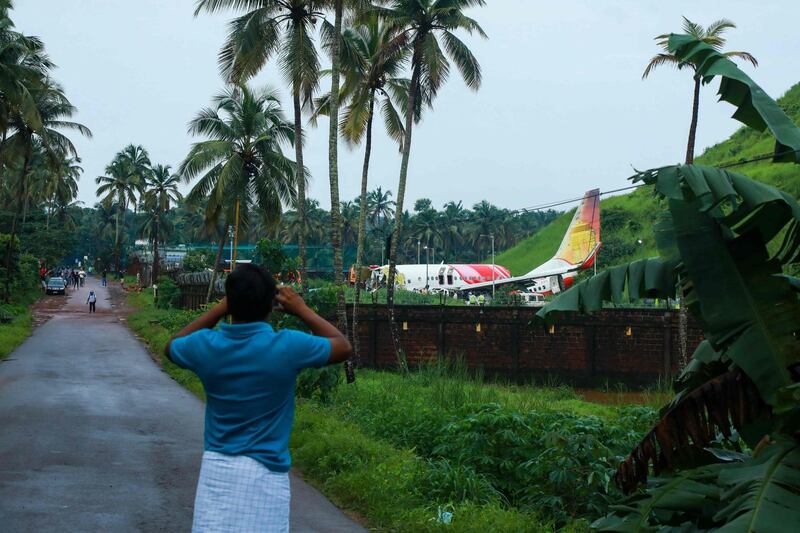 A man takes pictures with his mobile phone near the wreckage of the Air India Express jet. AFP