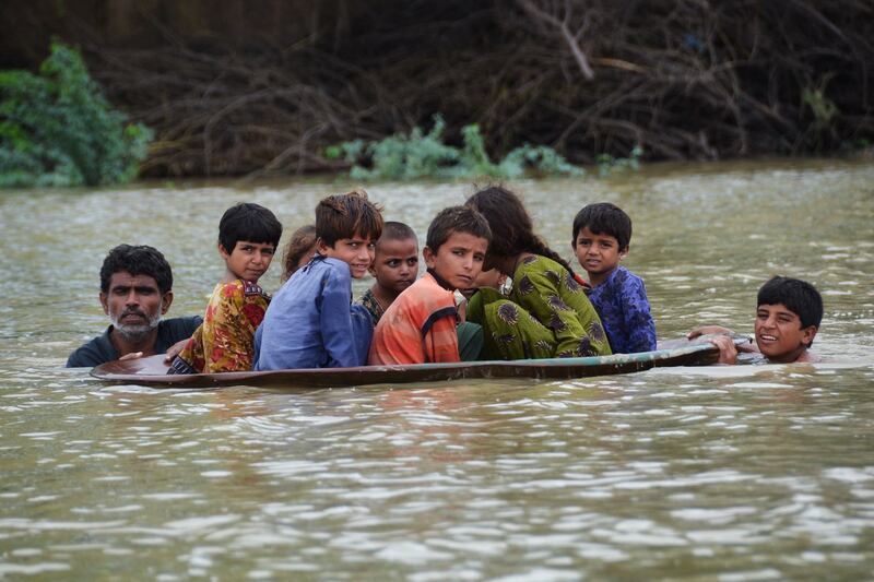A satellite dish makes an unlikely raft for children after floods in Balochistan province, Pakistan, on August 26. AFP
