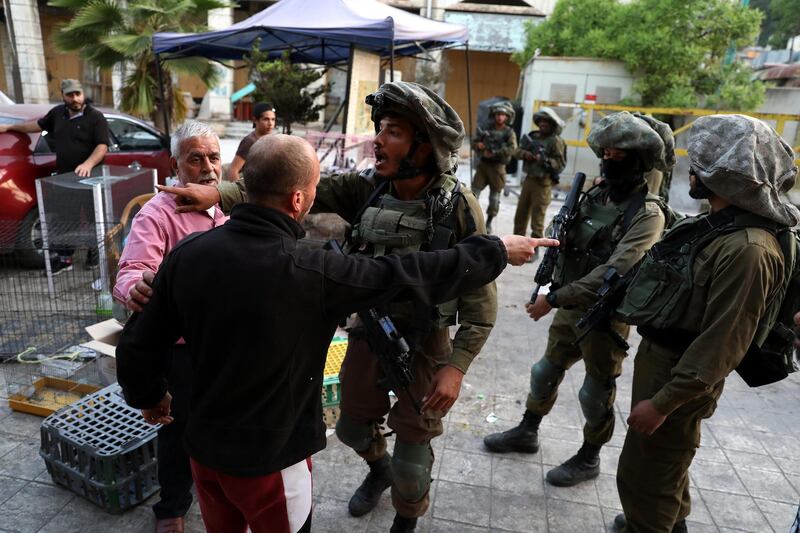 Israeli soldiers on patrol stop Palestinians in the Old City of the West Bank town of Hebron.  EPA