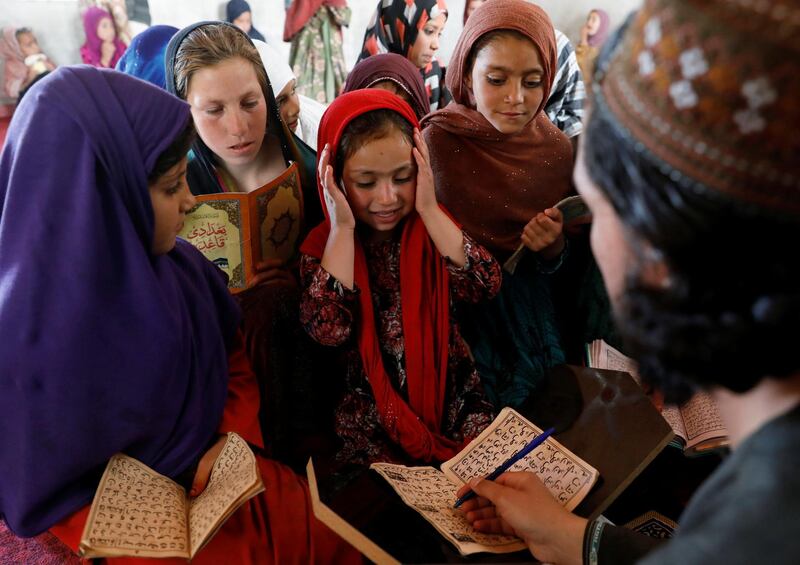 An Internally displaced Afghan girl reacts as she reads the Quran at a mosque during Ramadan, in Kabul, Afghanistan. Reuters