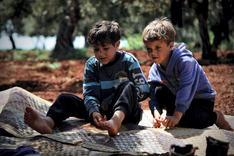 Esara'a son, Jamal and Bara ten and eleven years old sitting on a blanket playing together with a glass ball.