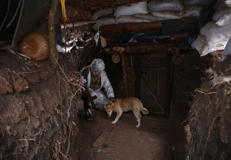 A Ukrainian soldier pets a dog in a trench at the front line. AFP