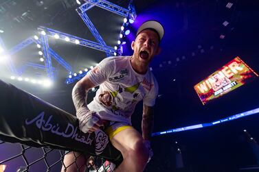 Jesse Arnett celebrates his victory against Ali AlQaisi (black shorts) in the Featherweight title fight at UAE Warriors 30. Etihad Arena, Abu Dhabi. Chris Whiteoak / The National