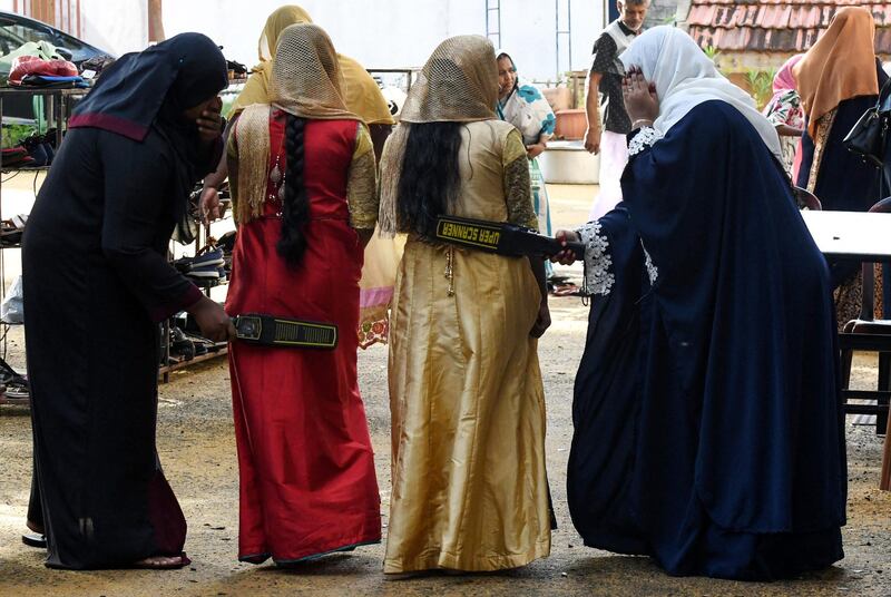 Sri Lankan Muslim women search devotees at the entrance of the Grand Mosque on the first day of Eid al-Fitr in Colombo on July 5, 2019. - Muslims around the world are celebrating the Eid al-Fitr festival, which marks the end of the fasting month of Ramadan. (Photo by LAKRUWAN WANNIARACHCHI / AFP)