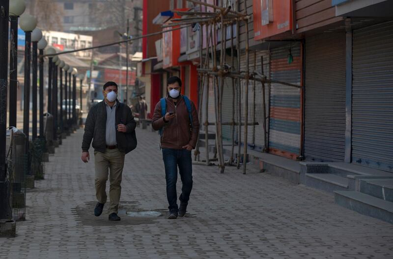 Kashmiri men wearing protective masks walk past closed shops as restrictions continued on the movement of people  in Srinagar, Indian controlled Kashmir. AP Photo
