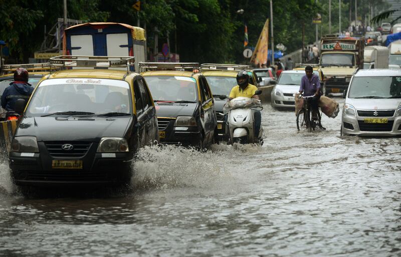 Indian commuters drive along a flooded road in Mumbai.  Punit Paranjpe / AFP