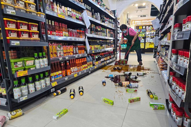 A supermarket worker cleans up broken bottles after the quake. AFP