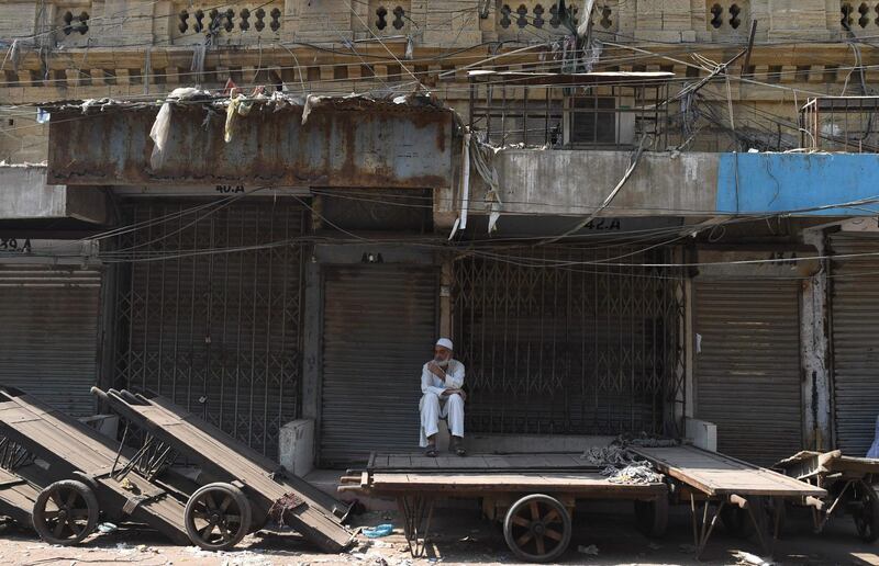 A man sits next to closed market shops during a protest in Karachi, Pakistan. Asif Hassan / AFP