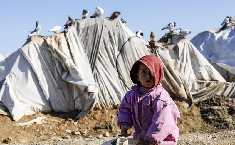 A child stands next to a pail of water outside a tent at Abu Al-Khashab camp in Deir Ezzor, Syria. AFP