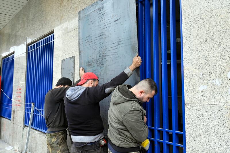 Workers install metallic barriers on the facade of a bank as a protective measure against vandalism in Tripoli, northern Lebanon.  EPA