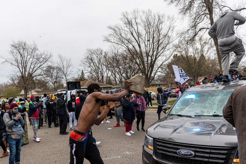 A man throws a rock to a police car as protesters clash with police after an officer reportedly shot and killed a black man in Brooklyn Center, Minneapolis, Minnesota.  AFP