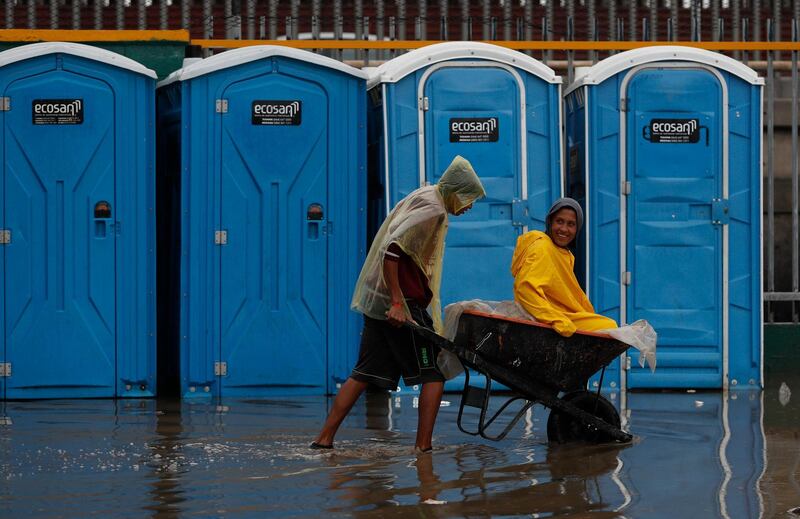 A man pushes a friend in a wheelbarrow through flood waters. AP Photo