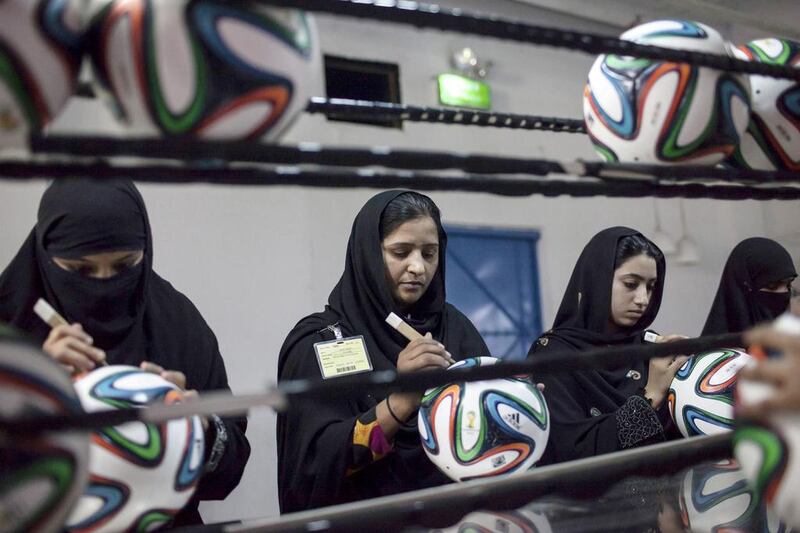 Employees conduct a final check to fix any cavities in the seams of balls. Sara Farid / Reuters

