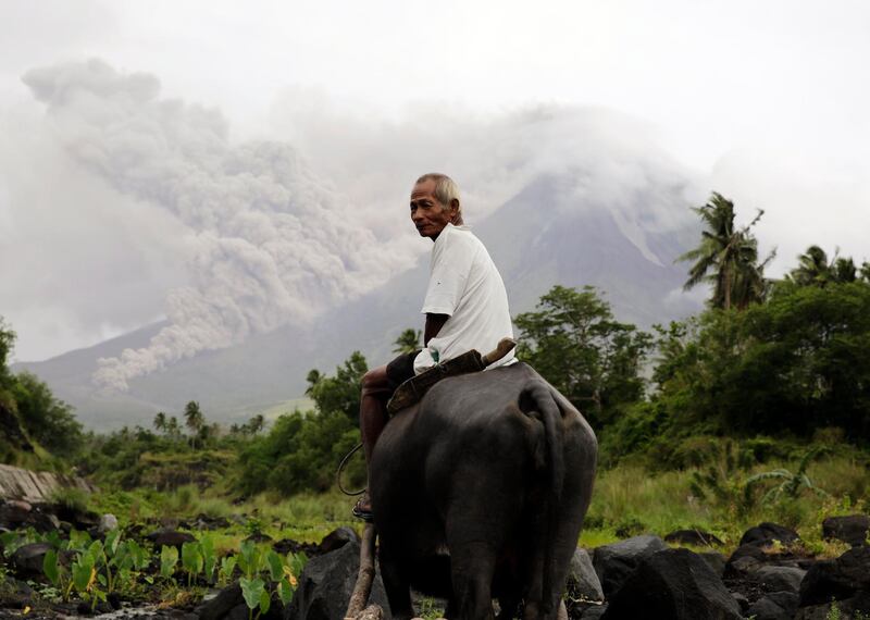 A Filipino villager rides a water buffalo along the slopes of rumbling Mayon Volcano as it spews ash in Legaspi city, Albay province, Philippines. Francis R. Malasig / EPA
