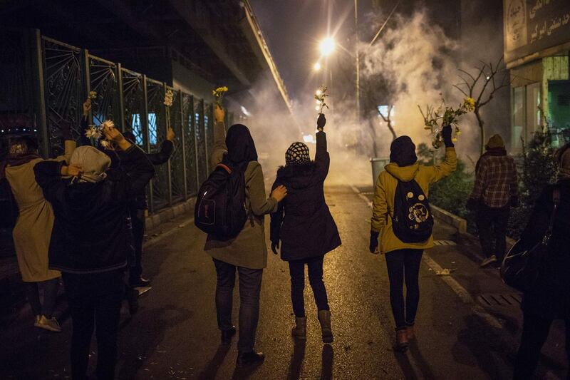 Iranian protesters hold flowers as riot police fire tear gas during a demonstration in front of Tehran's Amir Kabir University.  AFP