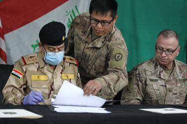 Coalition’s Brigadier General Vincent Barker watches Iraq’s Staff Major General Mohammad Fadhel Abbas sign a document during a pullout ceremony at the Qayyarah air base on March 26, 2020. AFP 