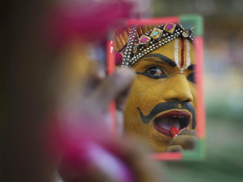 An Indian artist applies makeup in a mirror as he gets ready to perform during the Bathukamma festival dedicated to the Hindu Goddes Gauri in Hyderabad.  Mahesh Kumar A / AP Photo