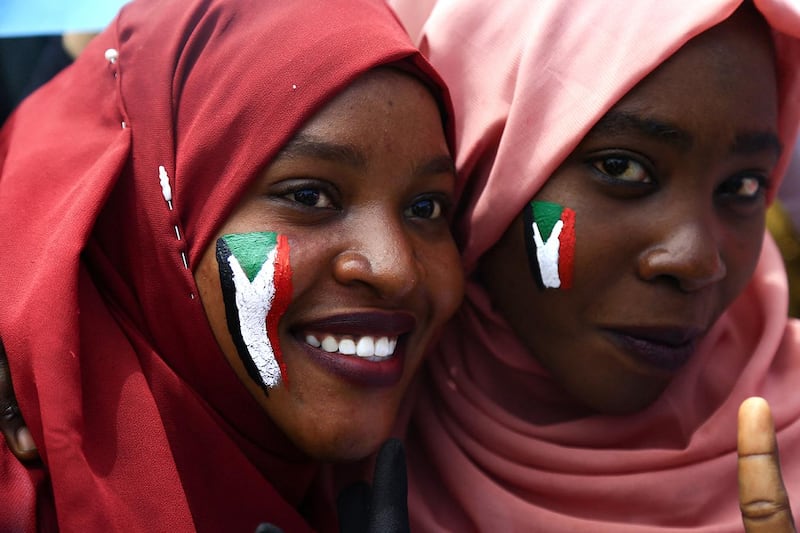 Sudanese women with national flags painted on their faces take part in a rally in the area of the military headquarters in the capital Khartoum on April 16, 2019. - Protesters in Sudan toughened their stance today by calling  for the dissolution of the transitional Military Council to replace it immediately with a civilian power. (Photo by ASHRAF SHAZLY / AFP)