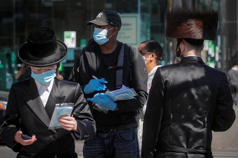 A member of New York City Test and Trace Corp. hands out masks to Ultra-Orthodox Jewish men during the outbreak of coronavirus disease in the Borough Park section of Brooklyn, New York, US. Reuters
