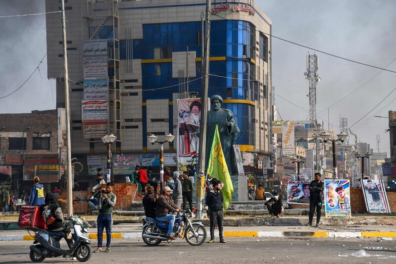 Protesters are pictured in a square as smoke billows following clashes between Iraqi police forces and anti-government protesters in Nasiriyah in southern Iraq.  AFP