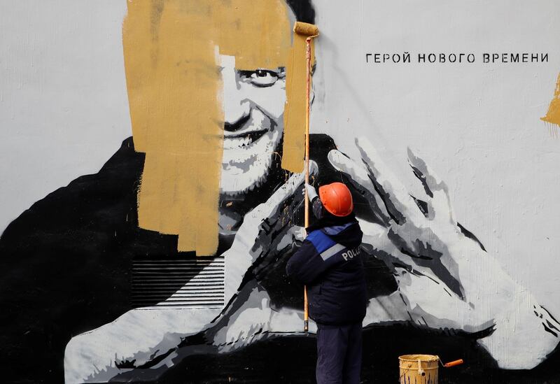A worker paints over graffiti depicting jailed Russian opposition politician Alexei Navalny in Saint Petersburg, Russia. The message reads: "The hero of the new age". Reuters