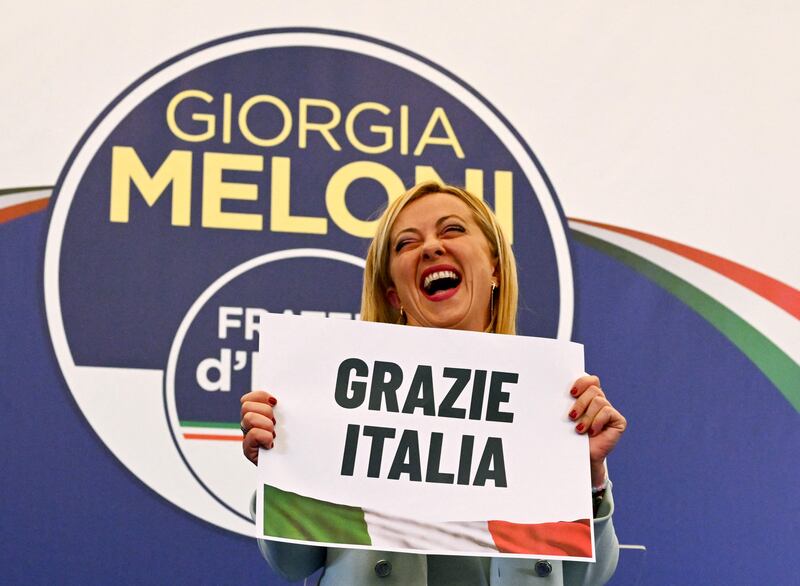 Leader of Italian far-right party Fratelli d'Italia (Brothers of Italy), Giorgia Meloni reacts as she holds a placard reading 'Thank You Italy' after she delivered an address at her party's campaign headquarters overnight on September 26, 2022 in Rome, after the country voted in a legislative election. AFP