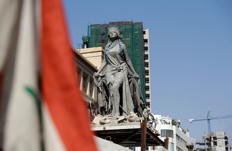 Demonstrators in Lebanon's capital march past a statue symbolising "Beirut rising from destruction" on their way towards the port on the first anniversary of the blast that ravaged  the city.