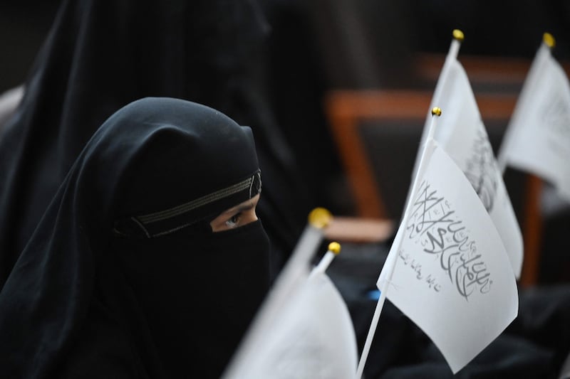 Veiled students hold Taliban flags as they listen to a speaker before the women marched in support of the Taliban. AFP