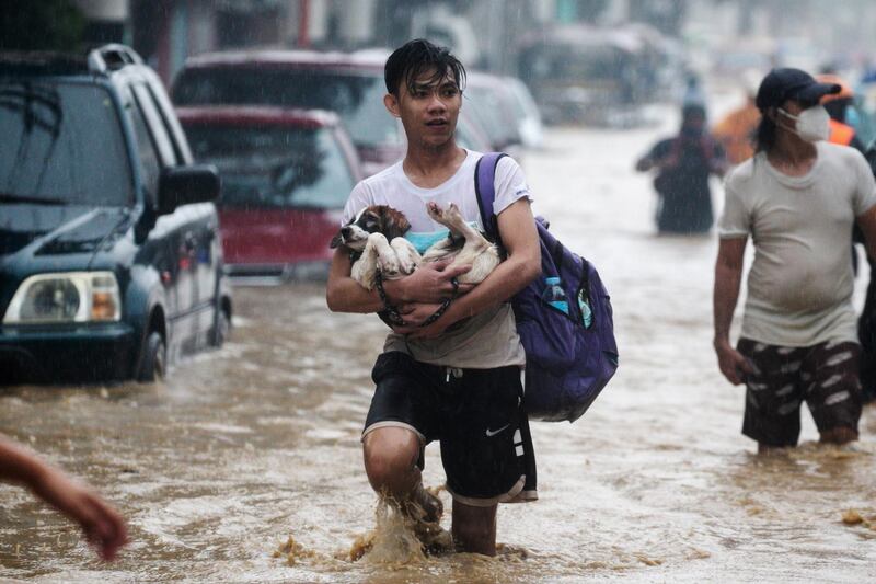 A man carries a dog as he evacuates from a flooded community following Typhoon Vamco, in Marikina. Reuters