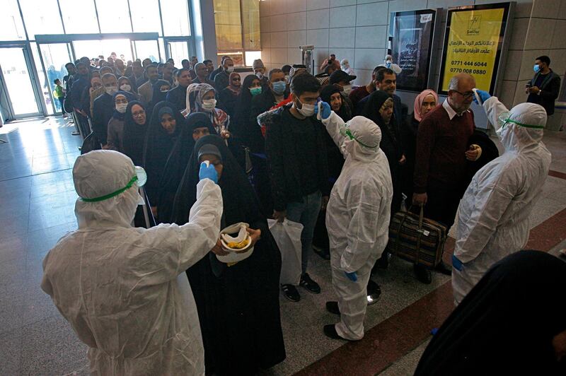 Medical staff check passengers arriving from Iran in the airport in Najaf, Iraq. AP