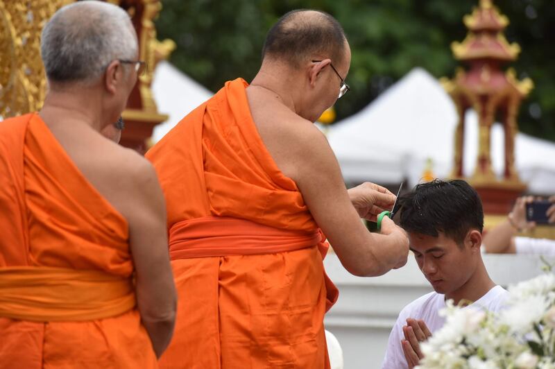 Buddhist monks cut the hair of the rescued coach Ekkapol Chantawong. AFP