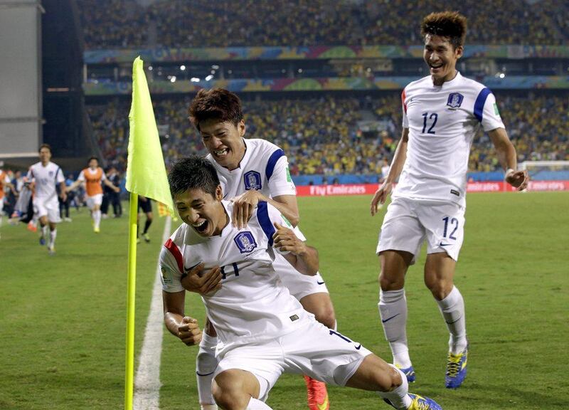 South Korea's Lee Keun-ho, front, is mobbed by teammates after he scores the opening goal in a 1-1 draw with Russia on Tuesday at the 2014 World Cup. Lee Jin-man / AP