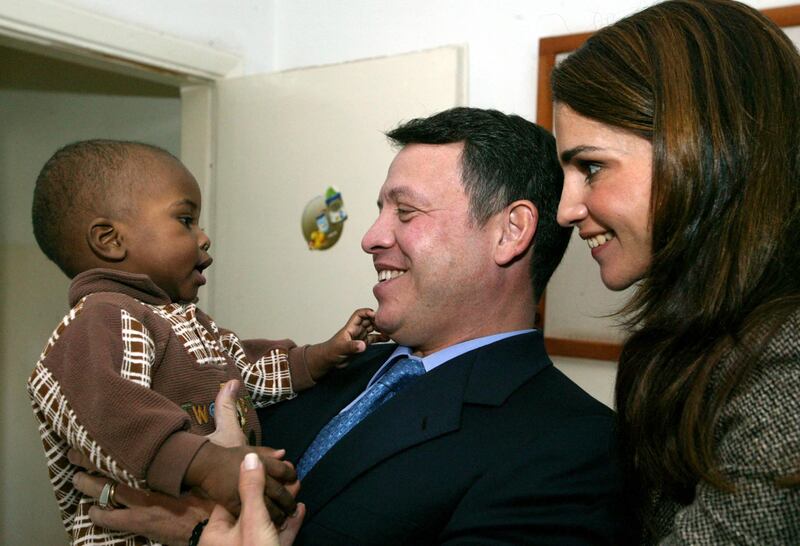 King Abdullah II and Queen Rania of Jordan playing with a little boy on a visit to the Hussein Foundation for orphans in Amman in November 2003. AFP
