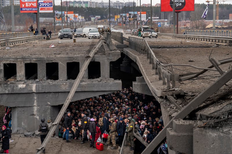 Ukrainians beneath a destroyed bridge in Irpin. AP Photo