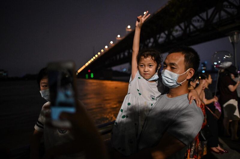 Residents wearing face masks are seen next to the Yangtze River in Wuhan in China's central Hubei province. Various parts of China have been hit by continuous rain since June, with the damage adding pressure to a domestic economy already hit by the coronavirus pandemic.  AFP