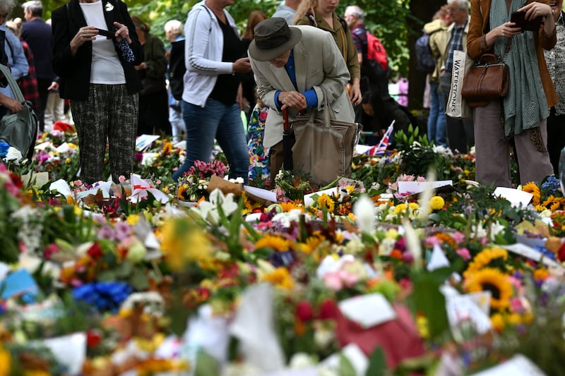 Members of the public look at flowers and tributes left in Green Park in London. AFP